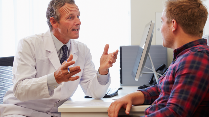 GP speaking to patient in their office