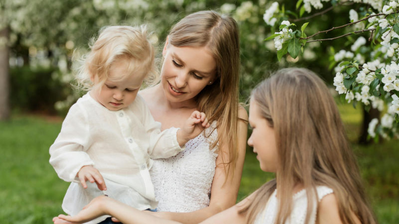 Mother and daughters pose candidly in a garden for a photo
